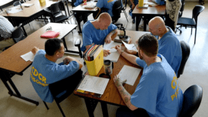 Four inmates learning and studying in prison uniforms in jail.