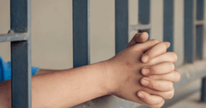 Folded hands from inside the jail cell